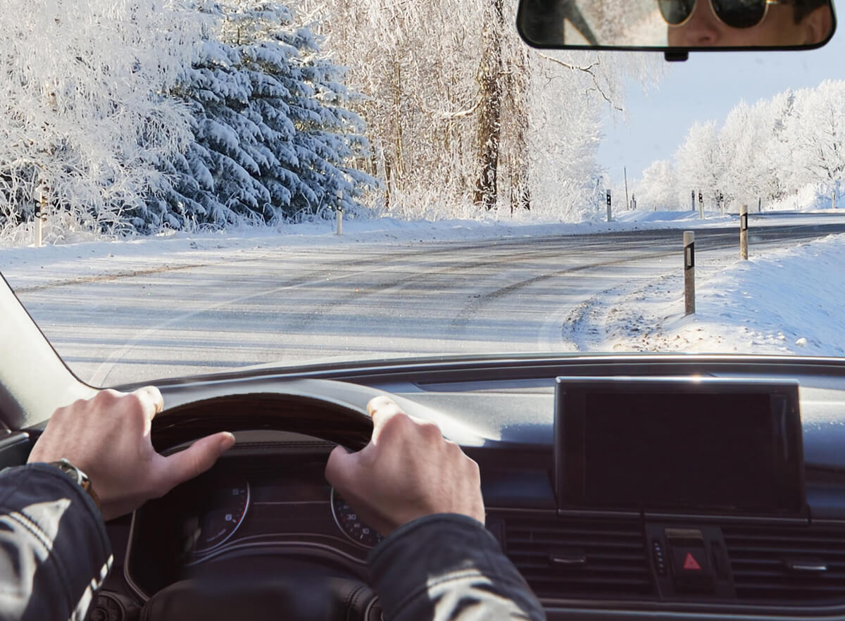 Person som kör bil på snötäckt väg